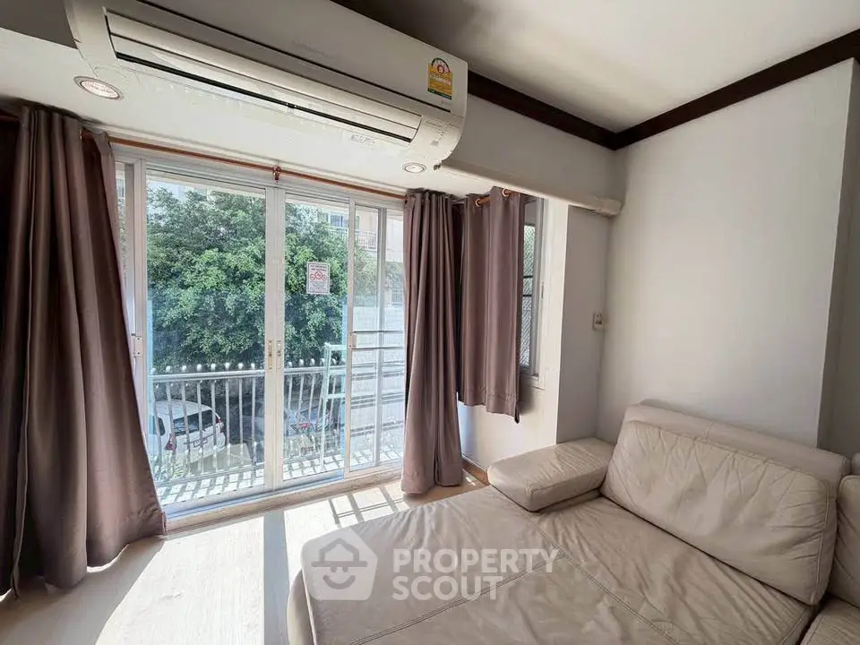 Bright living room with large windows and cozy sofa, offering a view of lush greenery.