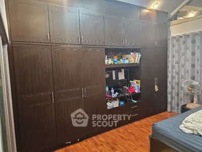 Spacious bedroom with large built-in wooden wardrobe and cozy decor