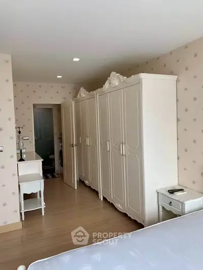 Elegant bedroom with classic white wardrobe and floral wallpaper, perfect for cozy living.