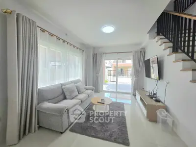 Modern living room with cozy gray sofa, stylish decor, and natural light from large windows.