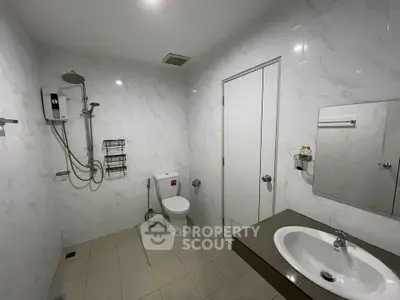 Modern bathroom with sleek fixtures and white marble tiles, featuring a shower and vanity sink.