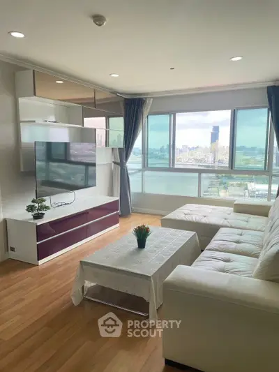 Spacious living room with large windows offering stunning city views, modern furniture, and elegant decor.