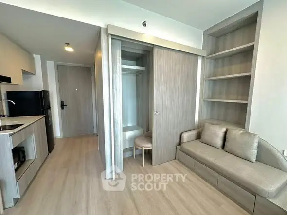 Modern studio apartment with sleek kitchen and cozy living area, featuring built-in storage and contemporary design.