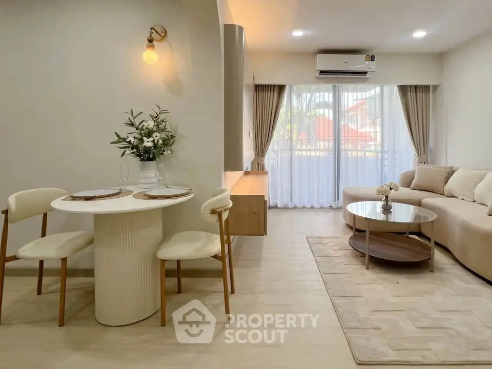 Elegant living room with modern decor, cozy seating, and natural light from large windows.
