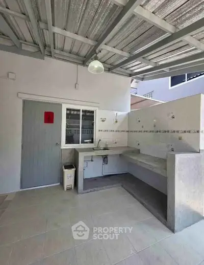 Modern outdoor kitchen with tiled countertops and metal roof, perfect for entertaining.