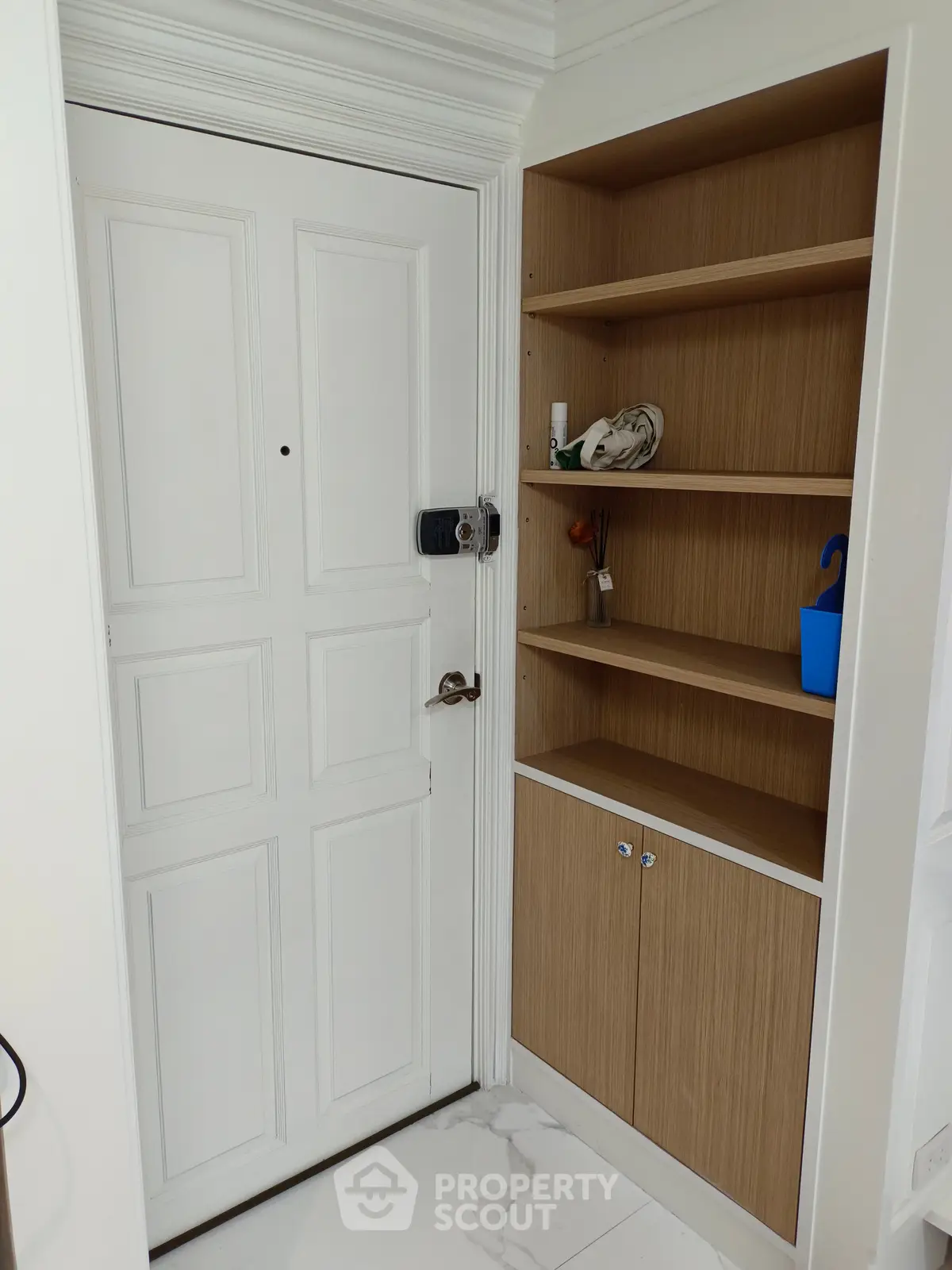 Stylish entrance with white door and wooden shelving unit, perfect for modern interiors.