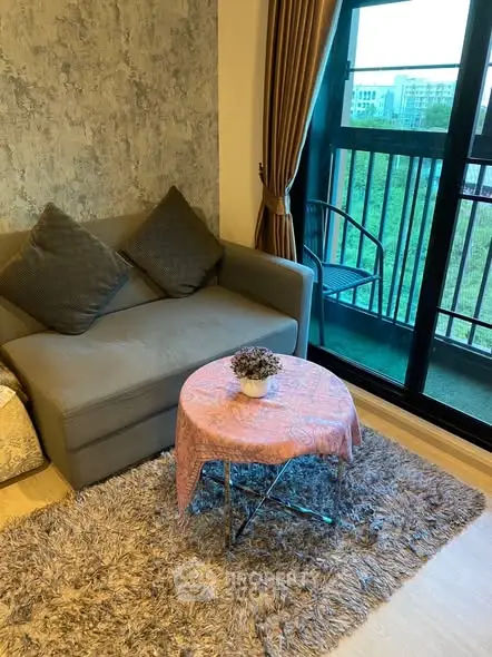 Cozy living room with modern sofa, stylish rug, and balcony view in urban apartment.