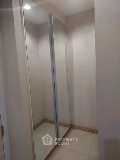 Spacious walk-in closet with mirrored sliding doors and elegant lighting.