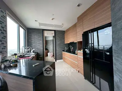 Modern kitchen with sleek wooden cabinets and large windows offering city views.
