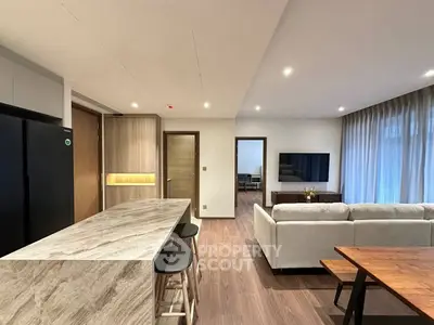 Modern open-plan living room with sleek kitchen island and cozy seating area, perfect for entertaining.