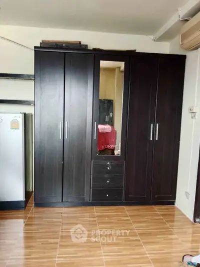 Spacious bedroom with elegant dark wood wardrobe and sleek flooring