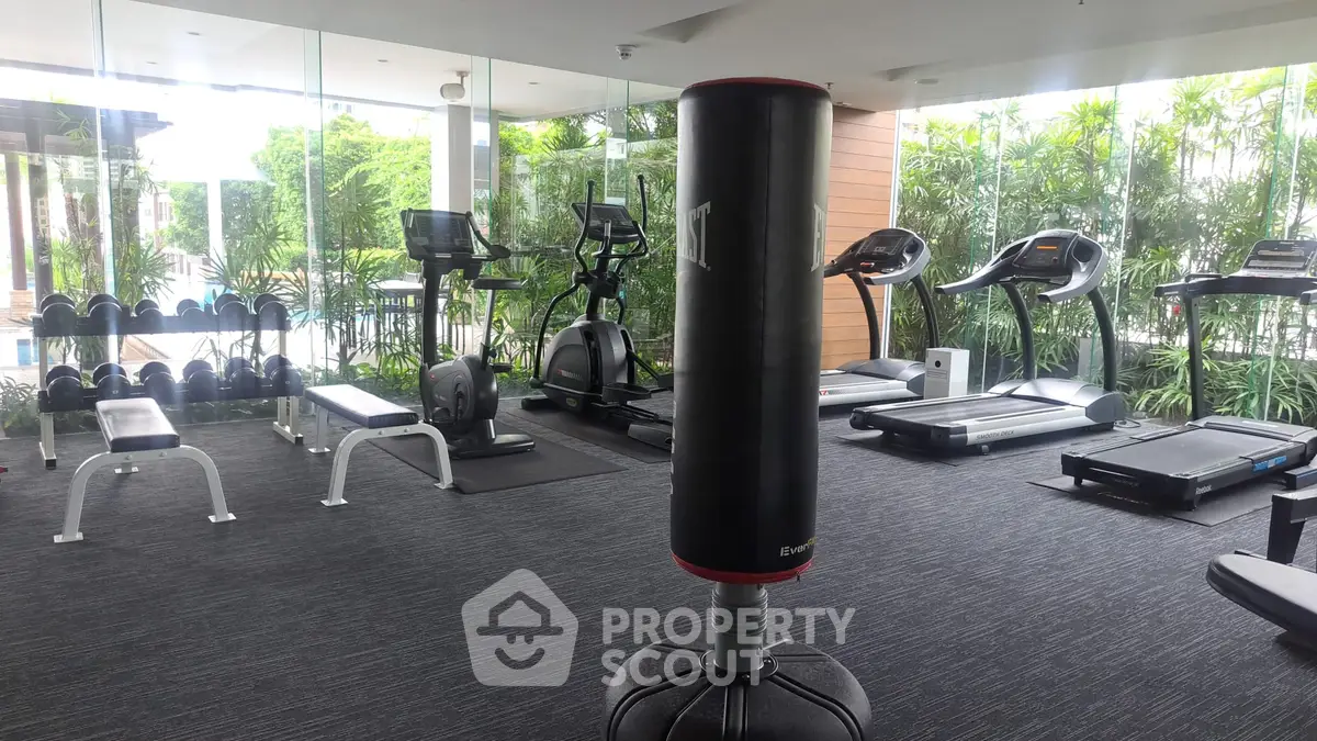 Modern gym with state-of-the-art equipment and lush garden views, perfect for fitness enthusiasts.