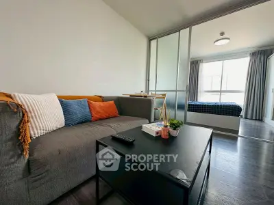 Modern living room with cozy sofa and view into stylish bedroom