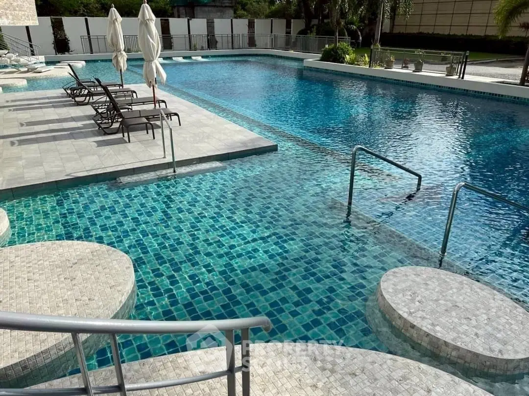 Luxurious swimming pool with elegant stone tiles and sun loungers in a serene setting.