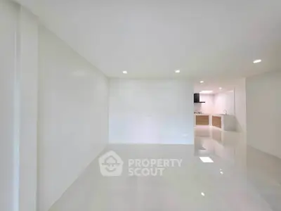 Spacious open-plan living area with modern kitchen in a bright, minimalist apartment.