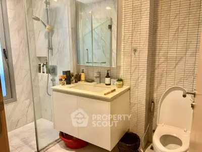 Modern bathroom with glass shower and sleek vanity in stylish apartment.