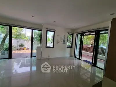 Spacious living room with large windows and garden view, perfect for natural light lovers.