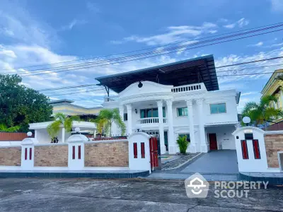 Stunning white mansion with grand entrance and spacious driveway in a serene neighborhood.