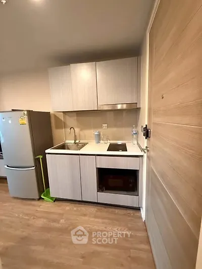 Modern compact kitchen with sleek cabinetry and appliances in a cozy apartment setting.
