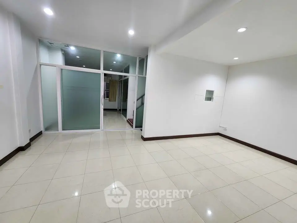 Spacious empty room with tiled flooring and glass partition, ideal for customization.