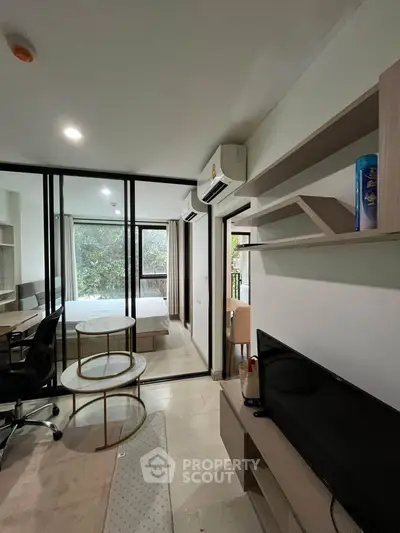 Modern studio apartment with glass partition, cozy living area, and natural light.