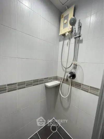 Modern bathroom shower area with sleek tile design and water heater.