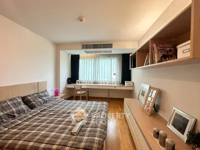 Spacious bedroom with modern decor and natural light, featuring a large bed and stylish workspace.