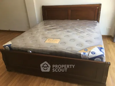 Spacious bedroom with elegant wooden bed frame and new mattress.