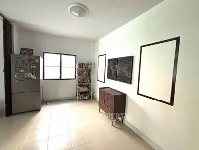 Spacious room with fridge and bookshelf, ideal for versatile use.