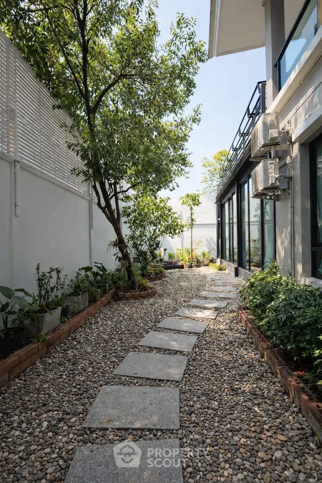 Charming garden pathway with lush greenery beside modern building exterior.