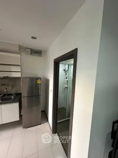 Modern kitchen with stainless steel fridge and sleek cabinetry in a compact layout.