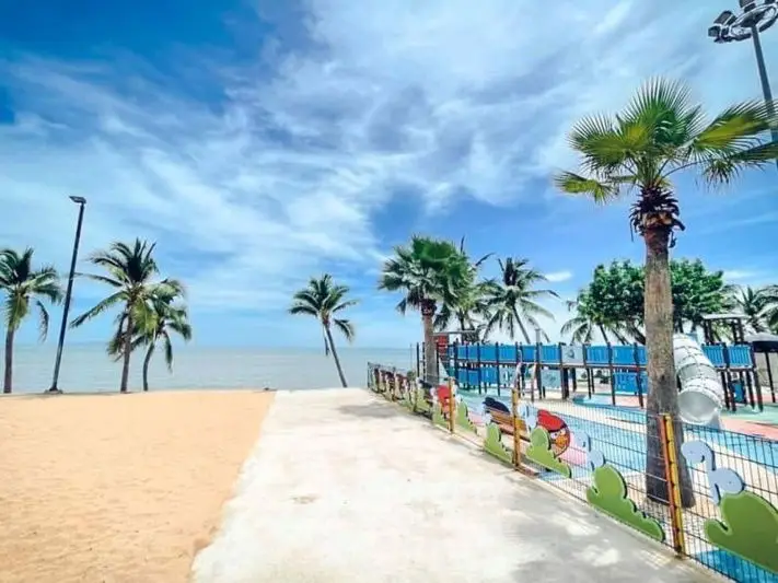 Stunning beachfront view with palm trees and a vibrant playground, perfect for family relaxation.