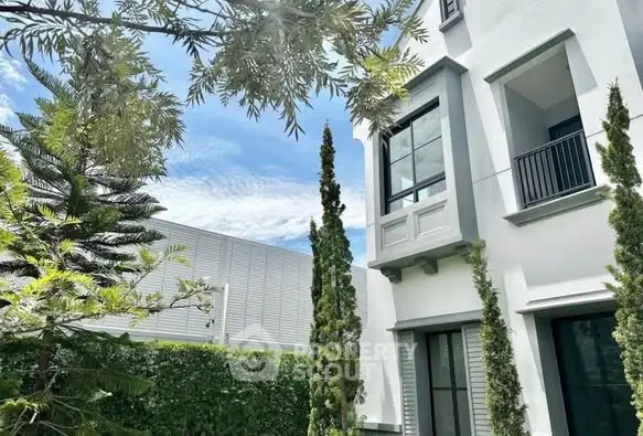 Elegant modern building exterior with lush greenery and stylish architecture.