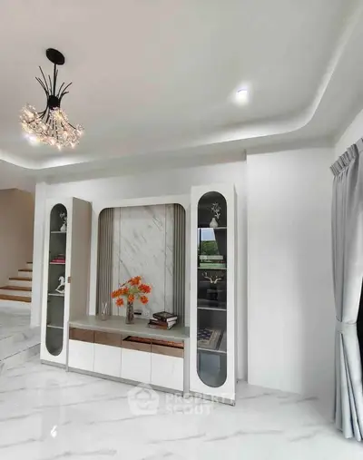 Elegant modern living room with stylish chandelier and built-in shelving, featuring sleek marble flooring and contemporary decor.