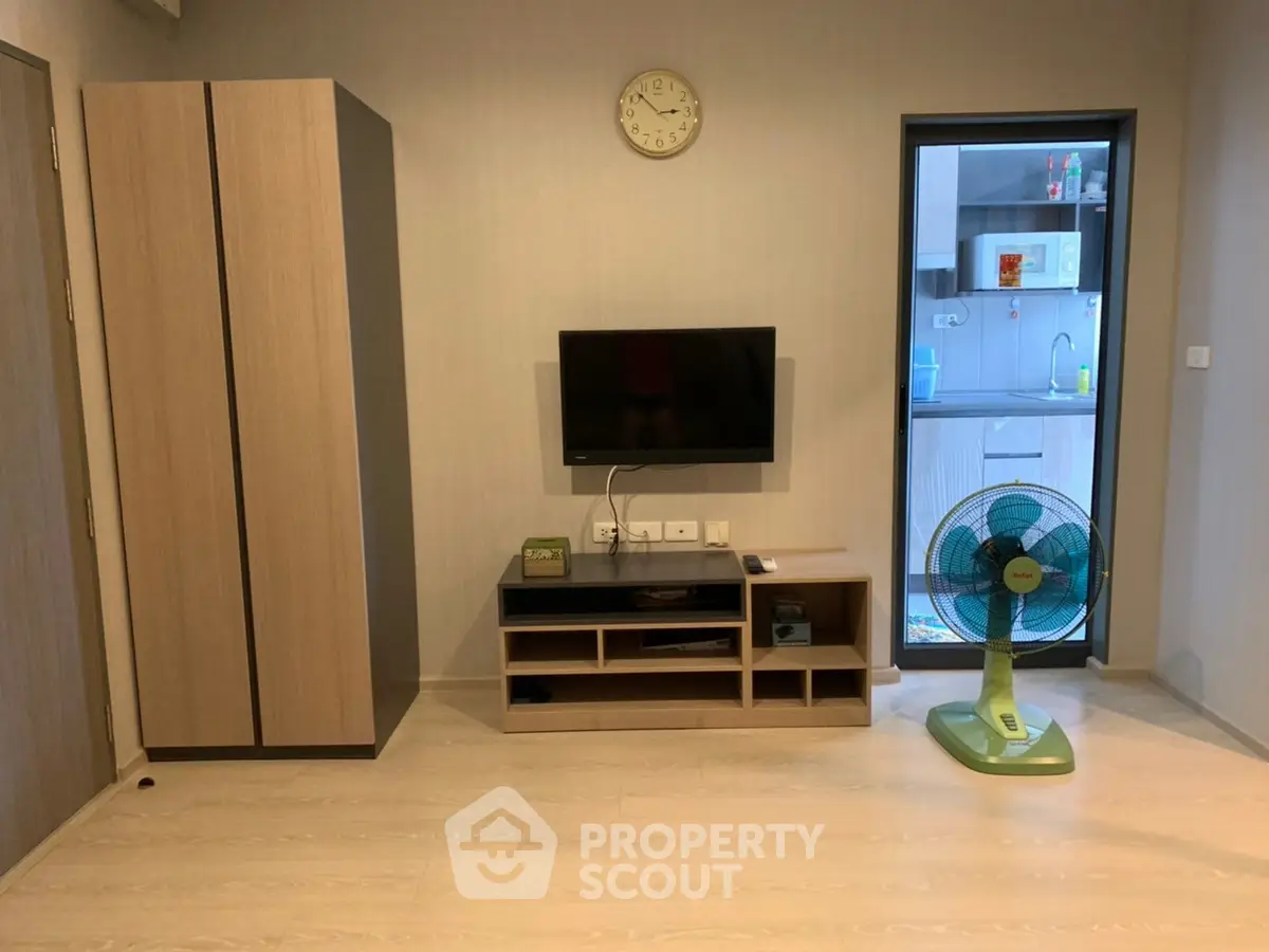 Modern living room with wall-mounted TV and adjacent kitchen view.