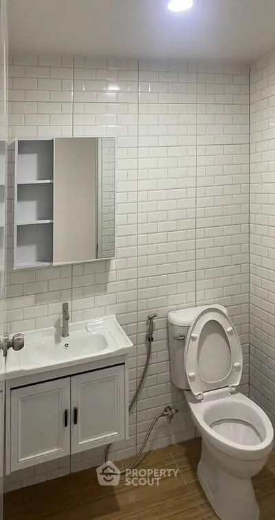 Modern bathroom with white tiles, vanity, and toilet in a sleek design.