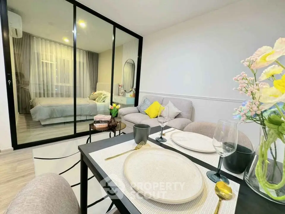 Modern open-plan living room with glass partition to bedroom, stylish decor, and dining area.