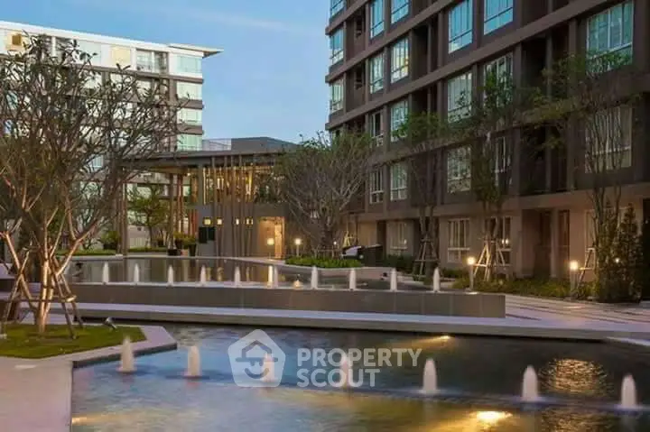 Modern apartment complex with serene water feature and lush landscaping.