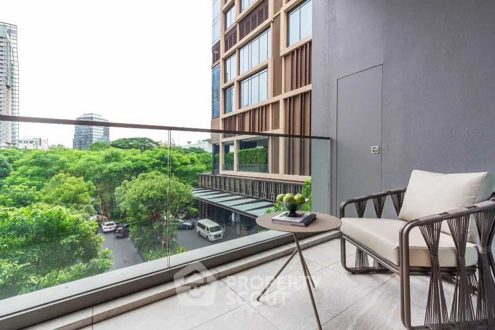 Modern balcony with glass railing and city view, featuring stylish outdoor furniture.