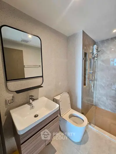 Modern bathroom with sleek fixtures and glass shower enclosure in contemporary apartment.