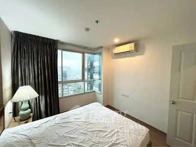 Cozy bedroom with city view, featuring a large window, air conditioning, and elegant lighting.