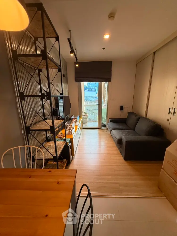 Modern compact living room with stylish shelving and cozy sofa, featuring a small balcony with city view.