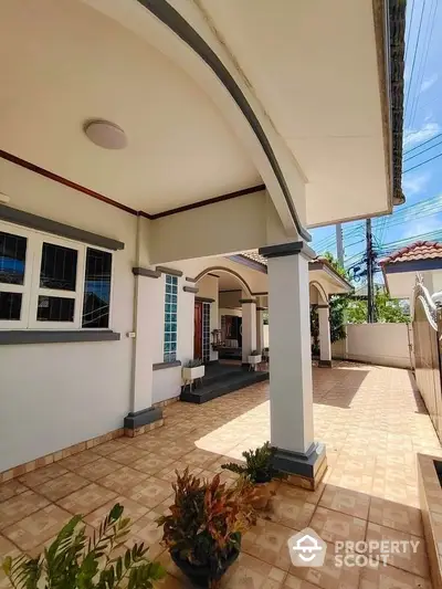 Charming single-story home with spacious tiled patio and elegant archways, perfect for outdoor relaxation.