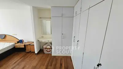 Spacious bedroom with built-in wardrobes and vanity area, featuring elegant wooden flooring.