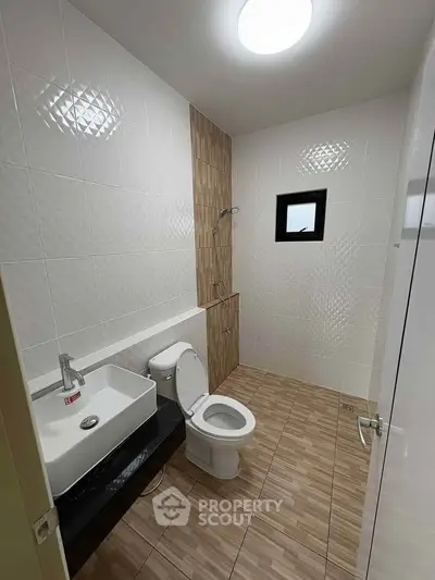 Modern bathroom with sleek design and neutral tiles, featuring a shower and contemporary fixtures.