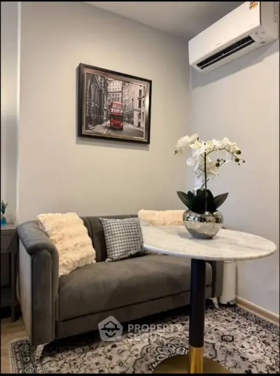 Cozy living room with elegant decor and air conditioning, featuring a plush sofa and stylish artwork.