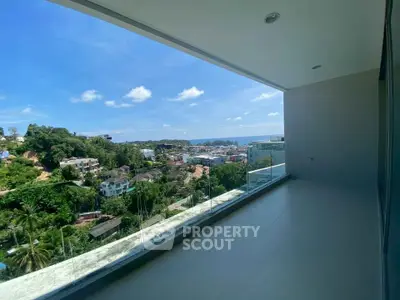 Spacious balcony with stunning panoramic view of lush greenery and distant ocean, perfect for relaxation.