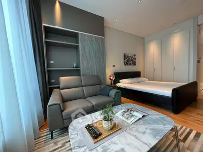 Modern studio apartment with stylish living area and cozy bedroom, featuring elegant furniture and natural light.