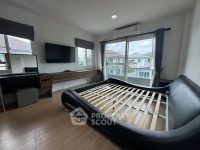 Spacious bedroom with modern bed frame and large windows offering natural light and neighborhood view.