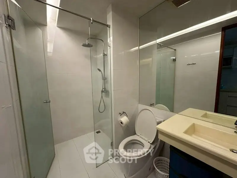 Modern bathroom with glass shower and dual sinks in a sleek real estate property.